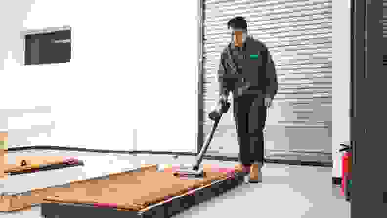 A man using a vacuum cleaner on a carpeted surface.