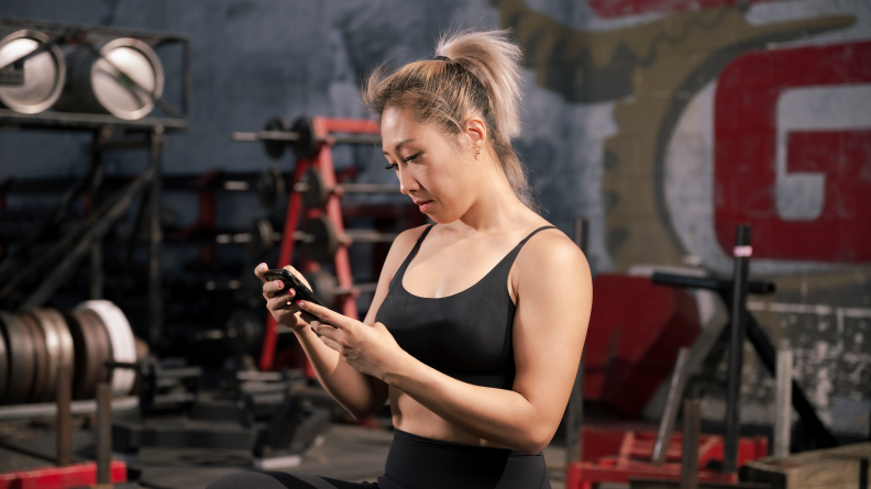 Person looking at smartphone mid-workout.