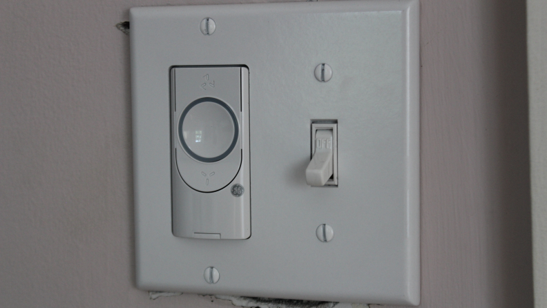 A white smart ceiling fan switch on a wall.