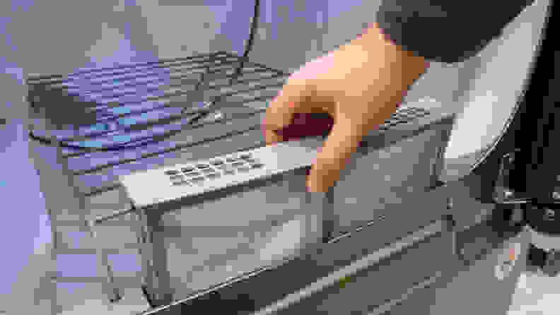 A hand reaches into frame to either remove or reinsert the lint trap. It is unclear from the image and the mystery shall live on throughout time.