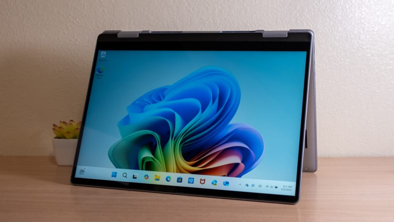 An open silver laptop sits on a brown desk