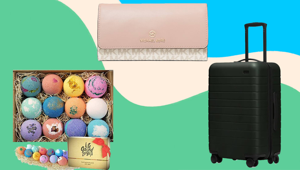 Assorter colorful bath bombs, a pink beige wallet and a black hardshell suitcase on a colored background