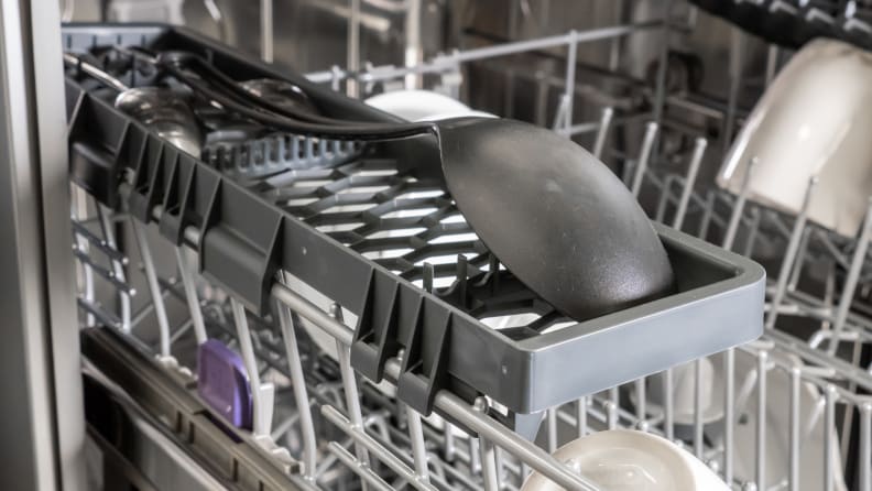 A spatula lays upside down on the side rack of the Beko DUT25401X dishwasher.