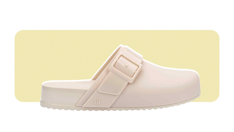 A flat clog with a strap and buckle, all made from PVC.