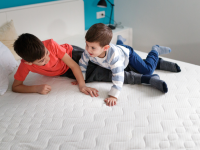 Two boys play on bare mattress