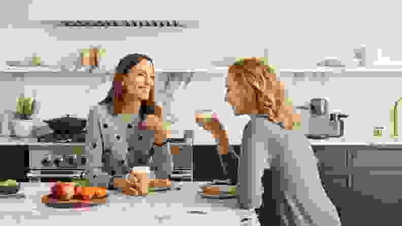 Two people enjoy coffee inside a kitchen.