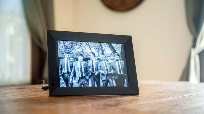 The Nixplay digital picture frame displays a black-and-white image of groomsmen.