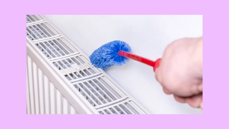 A person wipes a radiator clean with a duster.