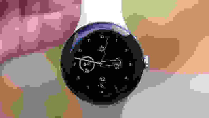 Our reviewer holds the Pixel Watch 2 by its white strap, showing off the watch's face.