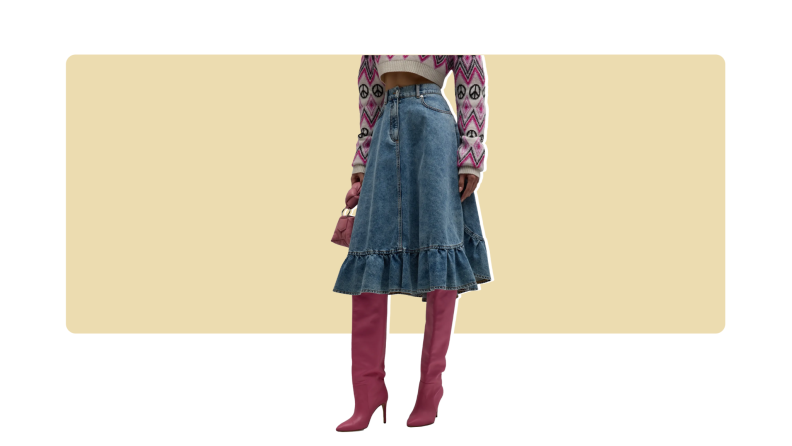A model wearing a knee-length denim skirt with ruffled details with knee-high burgundy boots.