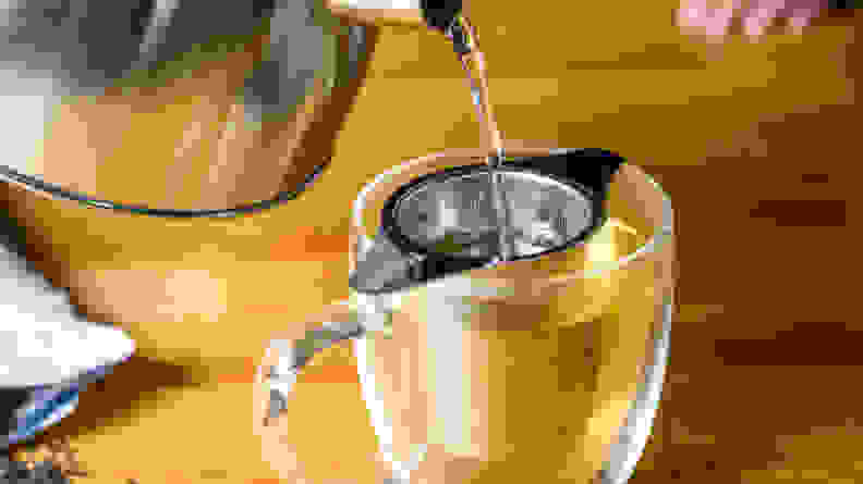 Person pouring hot water from kettle into a loose leaf tea infuser