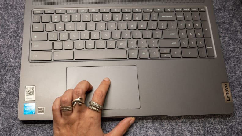 A hand grazes the touchpad of an open Lenovo Ideapad Gaming Chromebook.