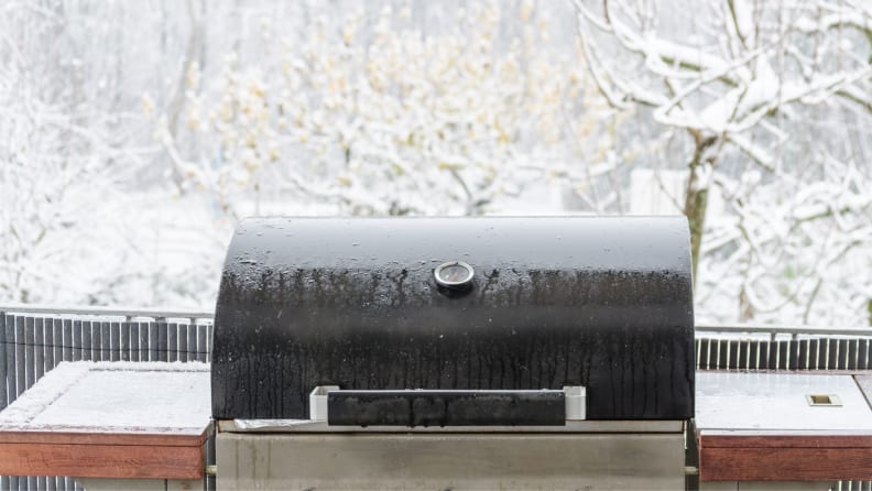 An uncovered grill sitting outside in the snow