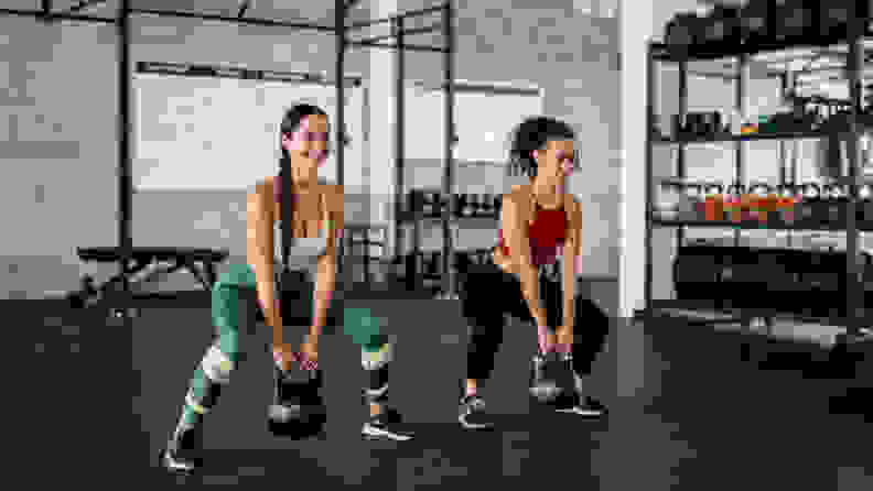 Two women squatting in the gym.