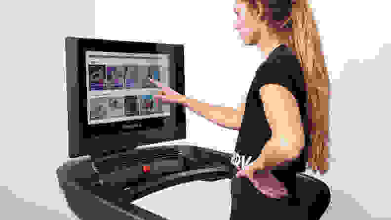 A person tapping the treadmill's touch screen.