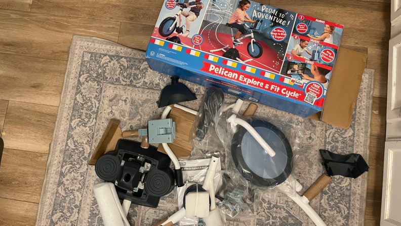 The Little Tikes Pelican Bike parts spread out on a rug