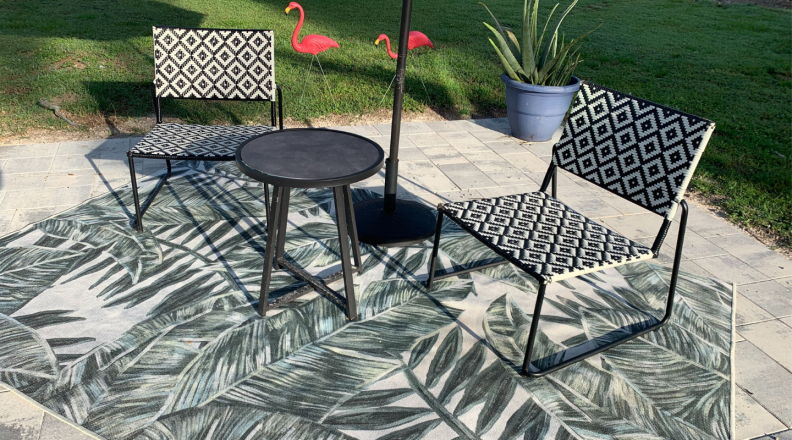 A machine washable rug, also known as a Ruggable, is pictured with a set of patio furniture.