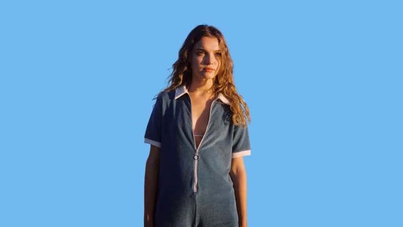 A model wears a terrycloth romper that is blue with white accents.