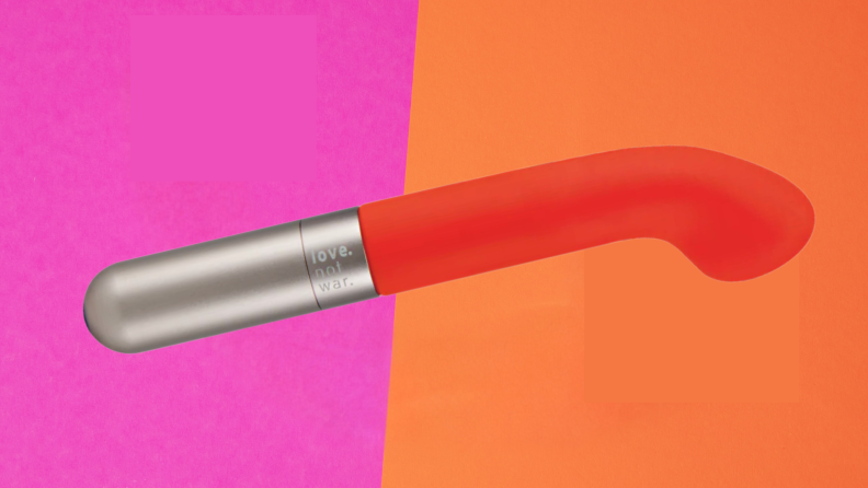 The orange Love Not War Liebe vibrator wand on top of a pink and orange surface.