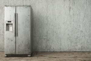 A free-standing refrigerator posed against a blank wall