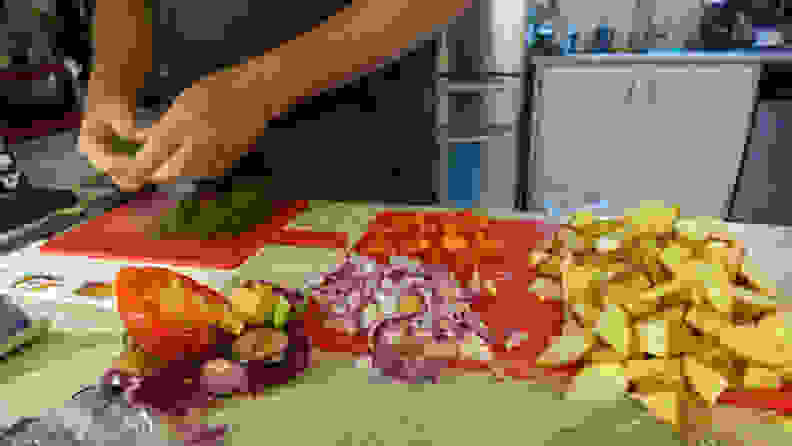 A person prepping herbs and vegetables on a kitchen counter.