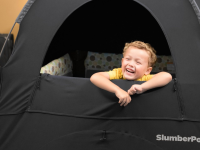 A child peeks out of a black SlumberPod.
