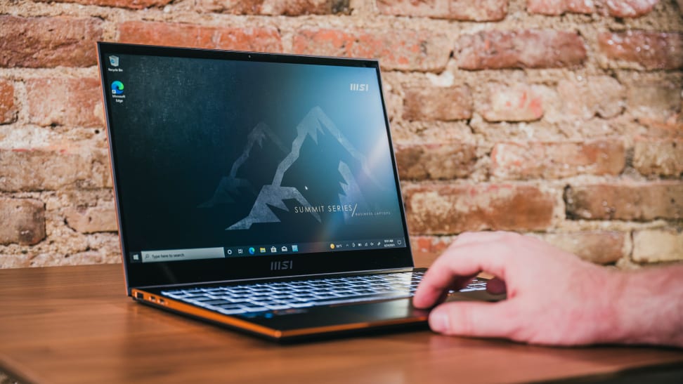 A hand placed on an open laptop sitting on a desk