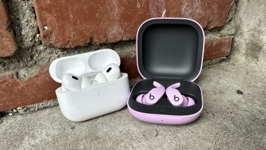 The Apple AirPods Pro 2 and Beats Fit Pro side by side on concrete steps with a brick wall in the background.