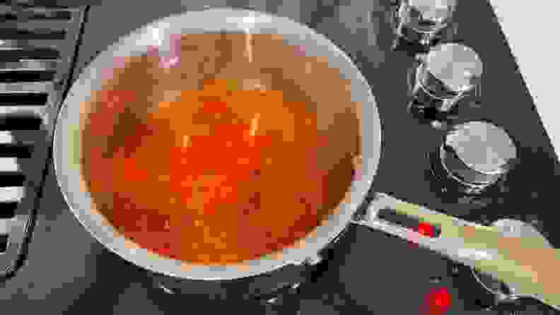 Pasta sauce being simmered inside of stainless steel pot with flared edges.