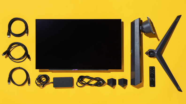 A monitor, stand, and cables laid out on a yellow background