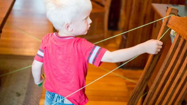 A young child follows a yarn obstacle course