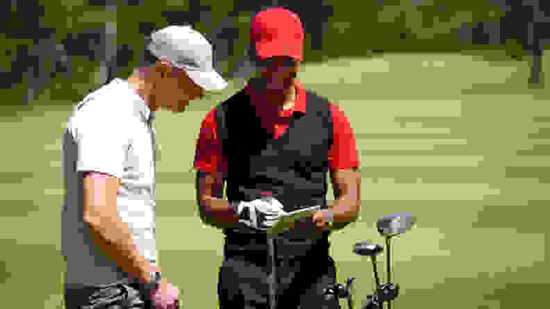 Two men on a golf course looking at a tablet