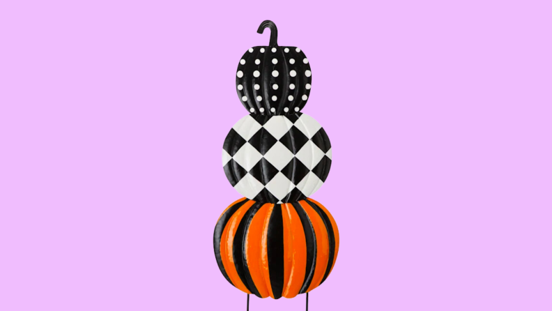 An image of a black, orange, and white pumpkin decoration, with three pumpkins in various patterns stacked together.
