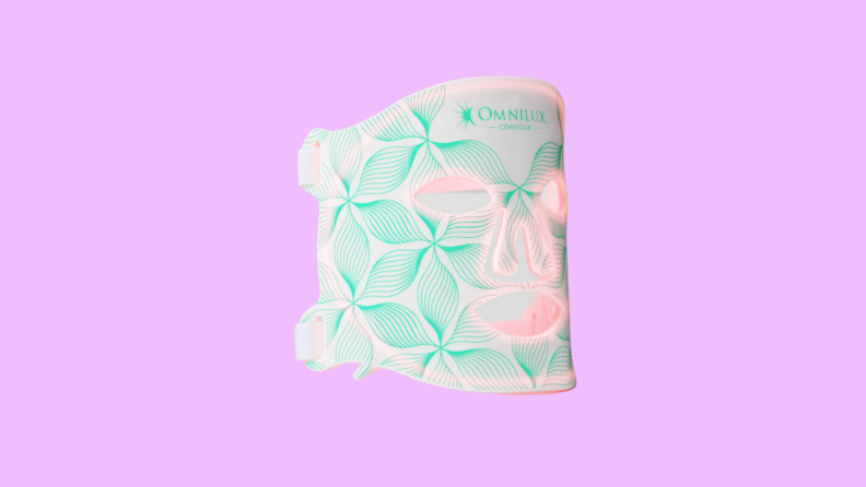 The pink, white, and teal Omnilux Contour Face Mask on a purple background.
