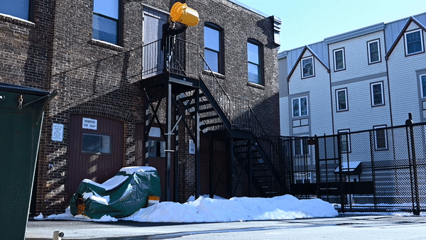 Gif of a yellow trash can being tossed off of a fire escape, cutting to a close up of the trash can bouncing off of the ground.