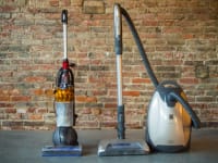 A bagged canister vacuum next to a bagless upright