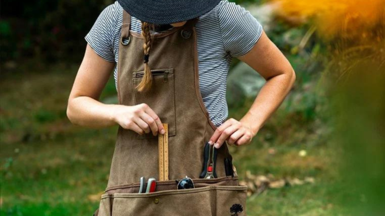 A person wearing a tool apron puts away items.