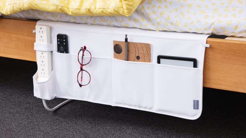 A bed caddy fits a power outlet, tablet, glasses, and notebook.