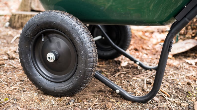A close-up of the wheels and stabilizing legs of of a wheelbarrow.