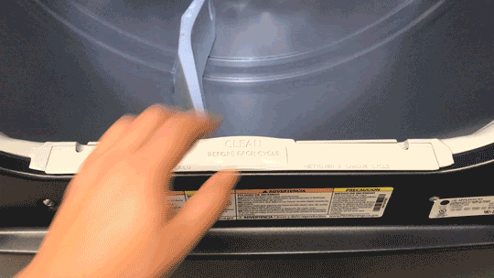 Person using hand to lift and display the lint trap on the GE Profile 900 Series PTD90EBPTRS Dryer.