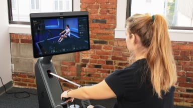 A woman taking a Peloton rowing class on the Row.