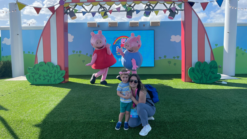 TV show cartoon characters Peppa and George pose with a parent and child