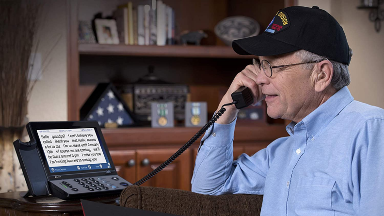 A senior talks on a phone with captions.