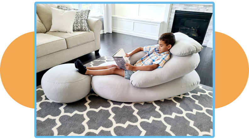 Child reclines on a Moon Pod while reading a book.