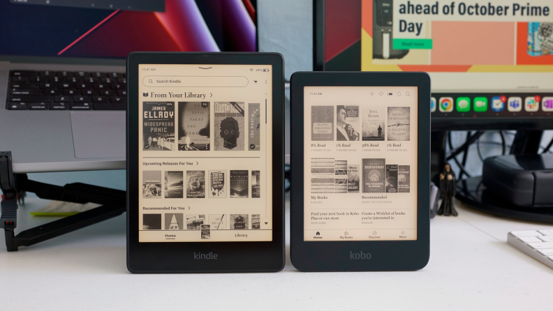 Two e-readers propped up vertically next to each other on top of a desk.