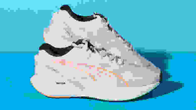 A pair of white Puma Run XX Nitro surrounded by a blue background.