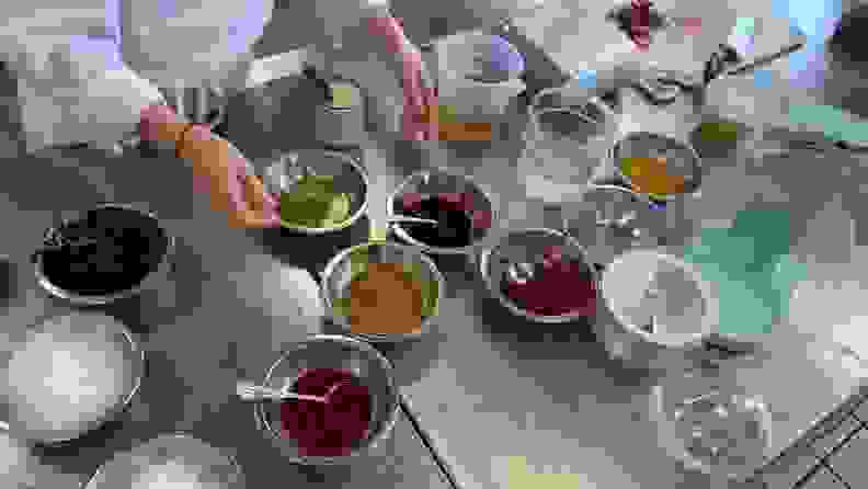 A variety of shaved ice toppings including condensed milk and flavored simple syrups, arranged on a stainless steel kitchen table.