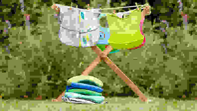 A variety of baby and toddler bibs drying on a rack outside