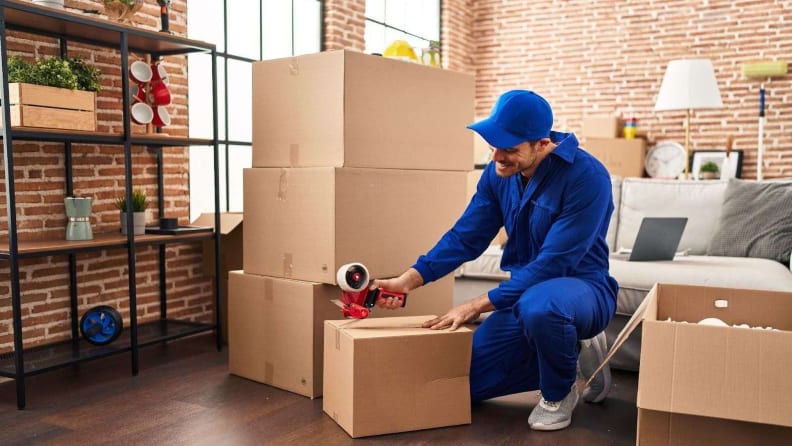 A mover happily taping up boxes for the move