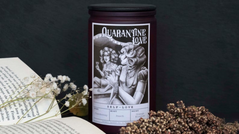 An image of the Quarantine Love candle in Self-love alongside a book and dried flowers.